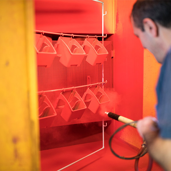 Powder-coated housings in manual coating process.
